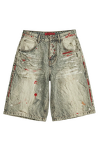 Distressed acid-wash denim shorts with red paint splatter 